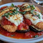 A delicious plate of chicken eggplant parmesan with crispy layers of chicken and eggplant, rich marinara sauce, and melted cheese garnished with fresh basil.