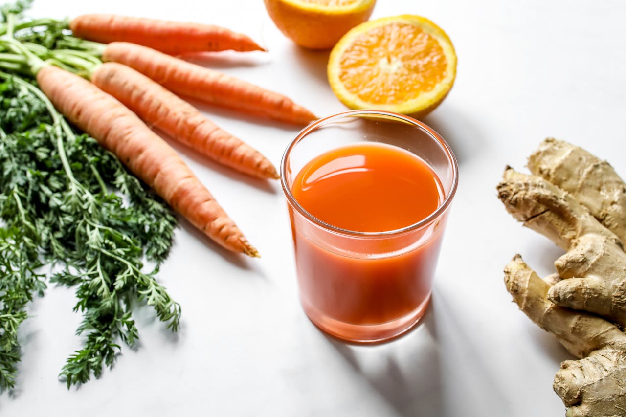 A glass of carrot juice with fresh carrots representing the theme "Is it OK to drink carrot juice every day?