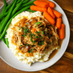 Tender Crockpot Chicken Pot Roast with carrots and gravy served over mashed potatoes with green beans on the side