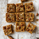 Baked Breakfast Oatmeal Pumpkin Bars: The Ultimate Cozy Morning Treat 5 Freshly baked pumpkin oatmeal breakfast bars topped with pecans and pepitas, sliced into squares on parchment paper – healthy fall meal prep idea.